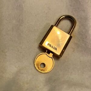 Authentic Gold Prada lock and key gold color in good condition. Some scratches